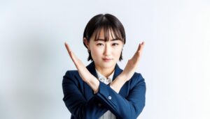 白背景で腕を交差して拒否を示すビジネスウーマン