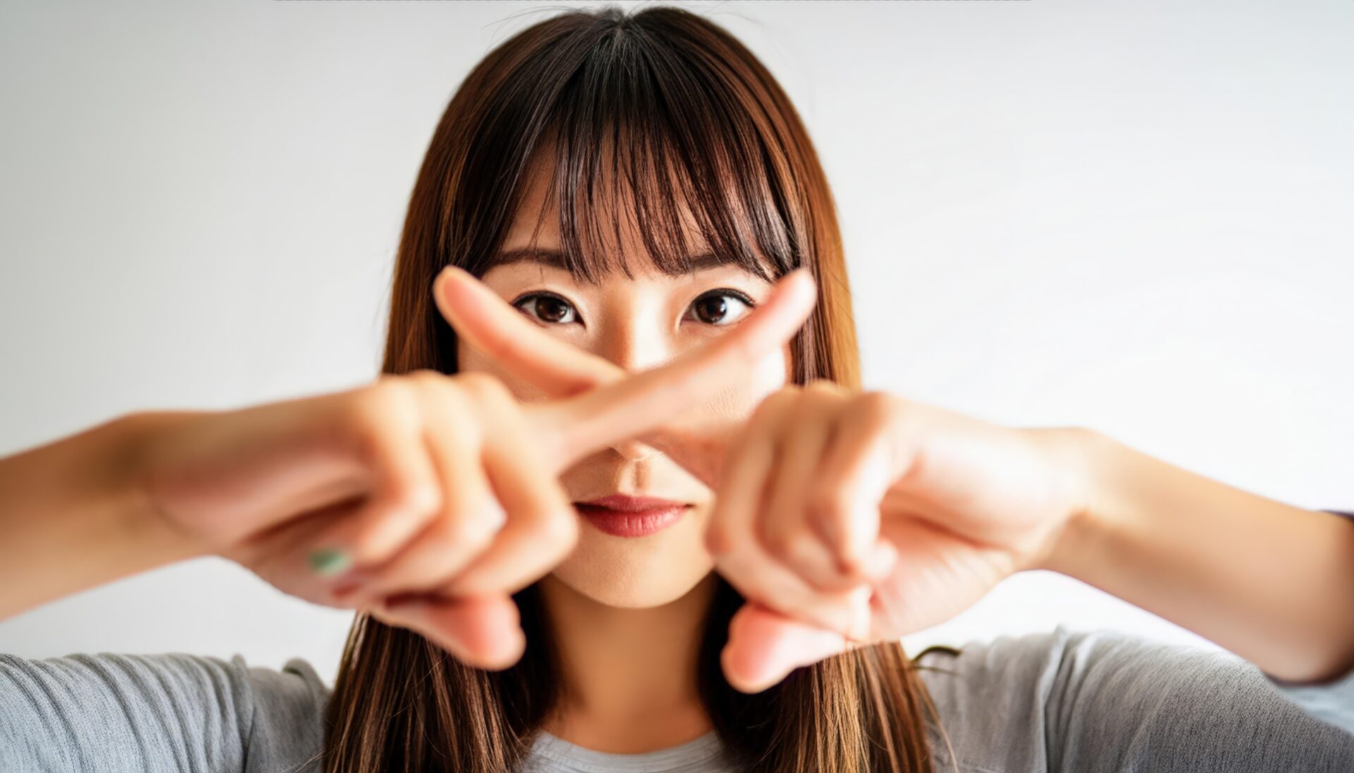 白背景で指をクロスしてNGサインを示す人