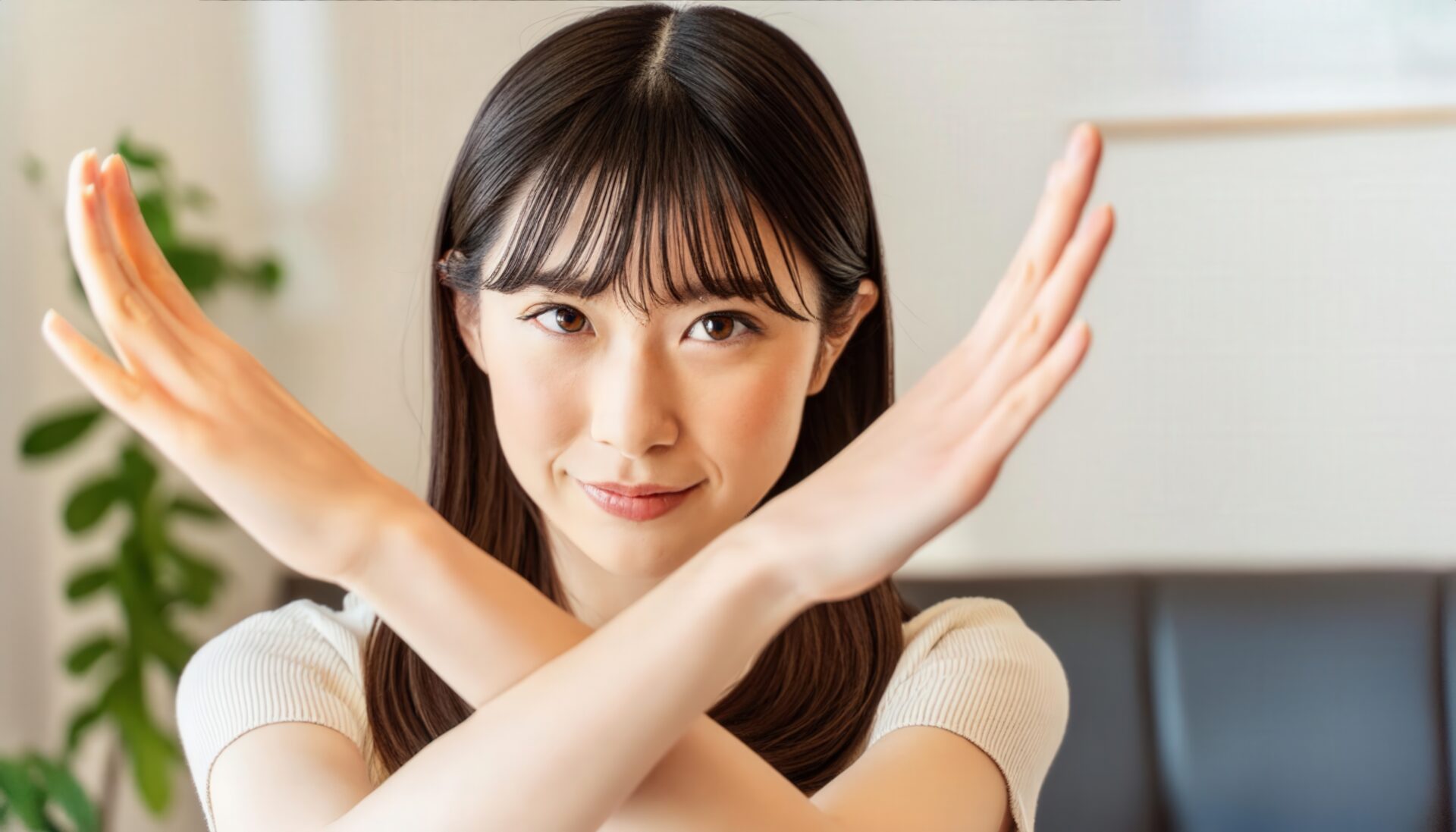 室内で腕をクロスしてNGサインを示す明るい服の人