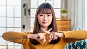 室内で指をクロスしてNGサインを示す人