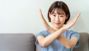 室内でストライプの半袖トップスを着て腕をクロスしてNGサインを示す人