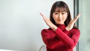 室内で赤いトップスを着て腕をクロスしてNGサインを示す人