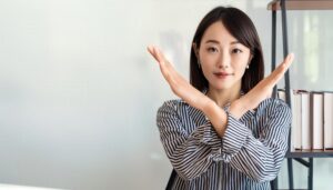 オフィスでストライプシャツを着て腕をクロスしてNGサインを示す人