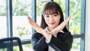 オフィスでストライプスーツを着て腕をクロスしてNGサインを示す人