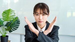 オフィスで黒いスーツを着て腕をクロスしてNGサインを示す人