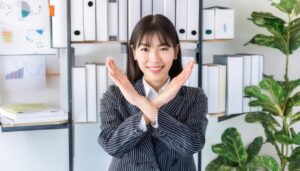 オフィスでストライプスーツを着て腕をクロスしてNGサインを示す人