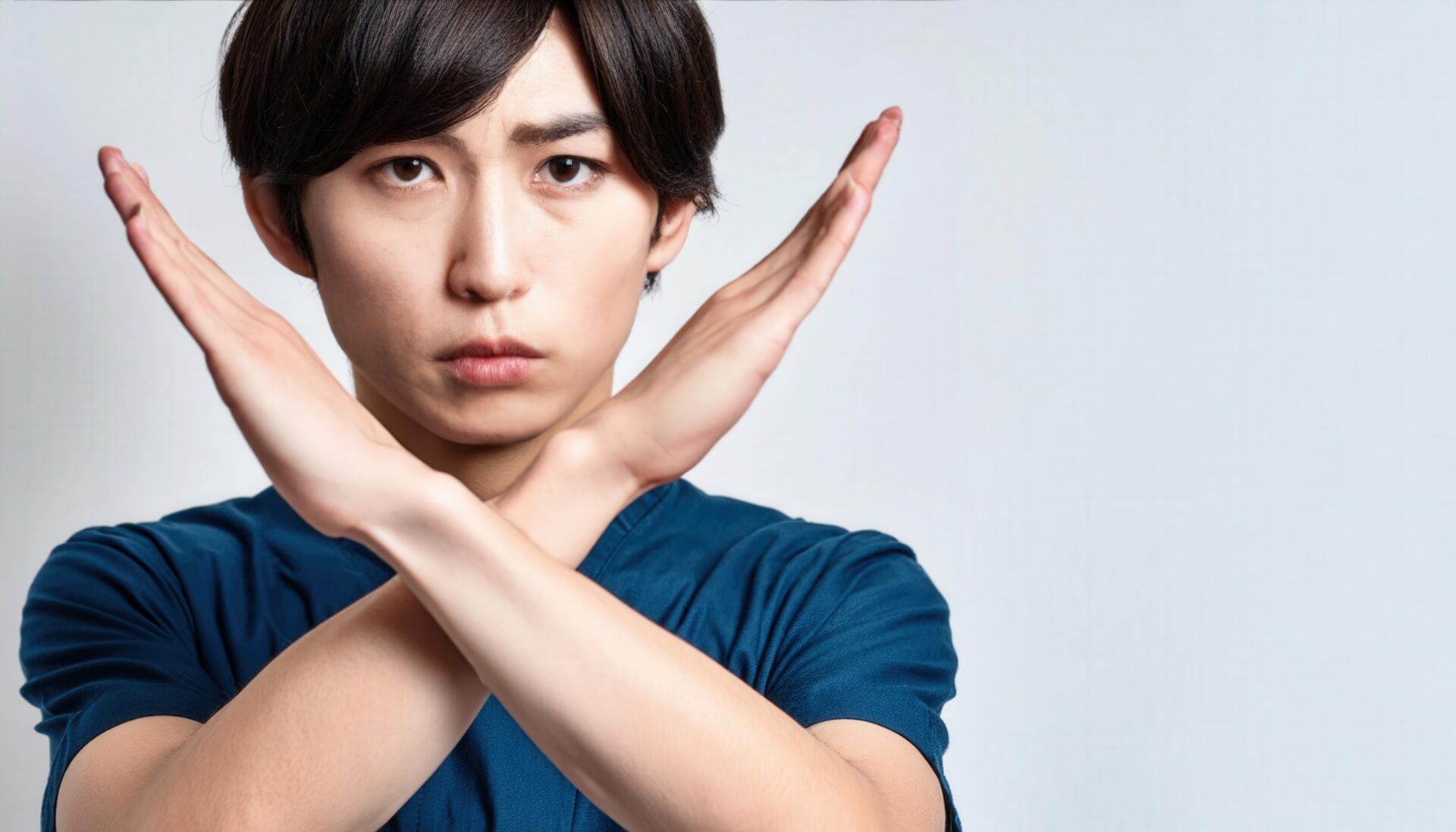 白背景でネイビーの服を着て腕をクロスしてNGサインを示す人