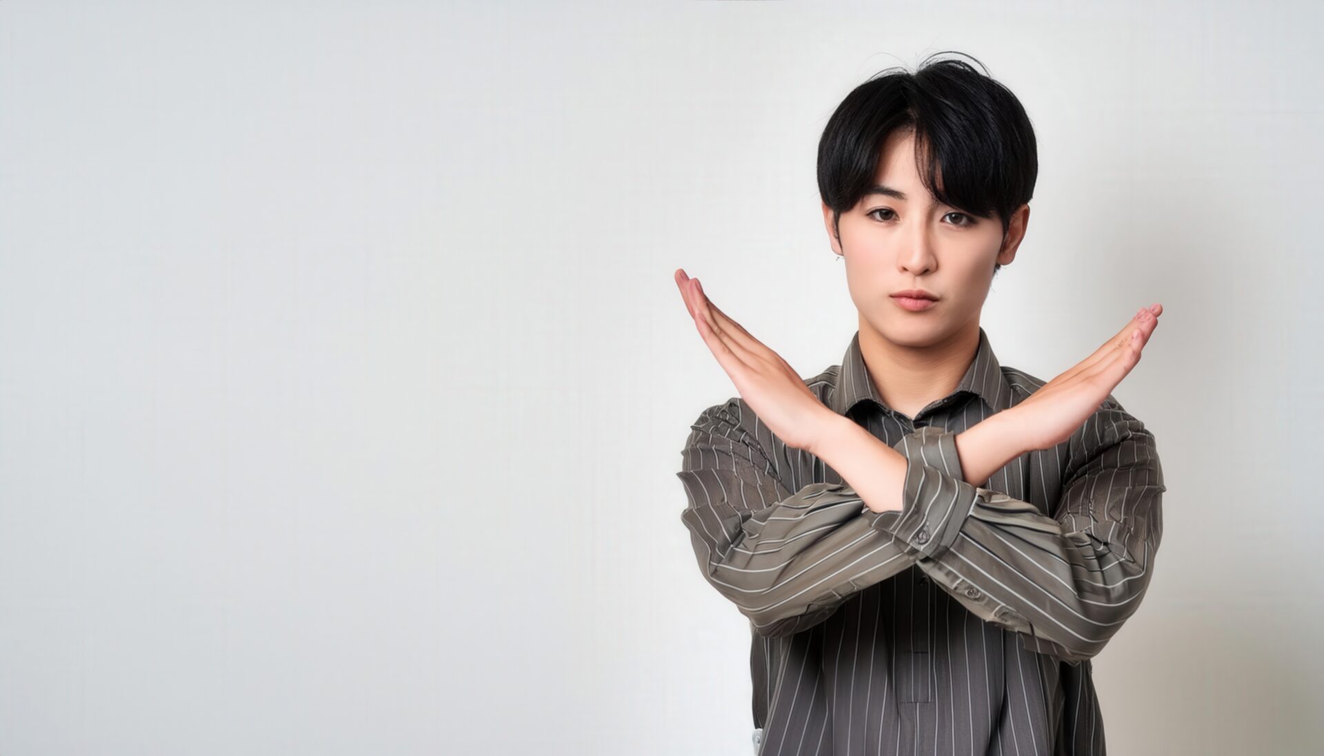 白背景でストライプシャツを着て腕をクロスしてNGサインを示す人