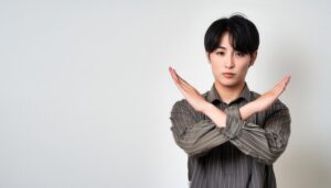 白背景でストライプシャツを着て腕をクロスしてNGサインを示す人