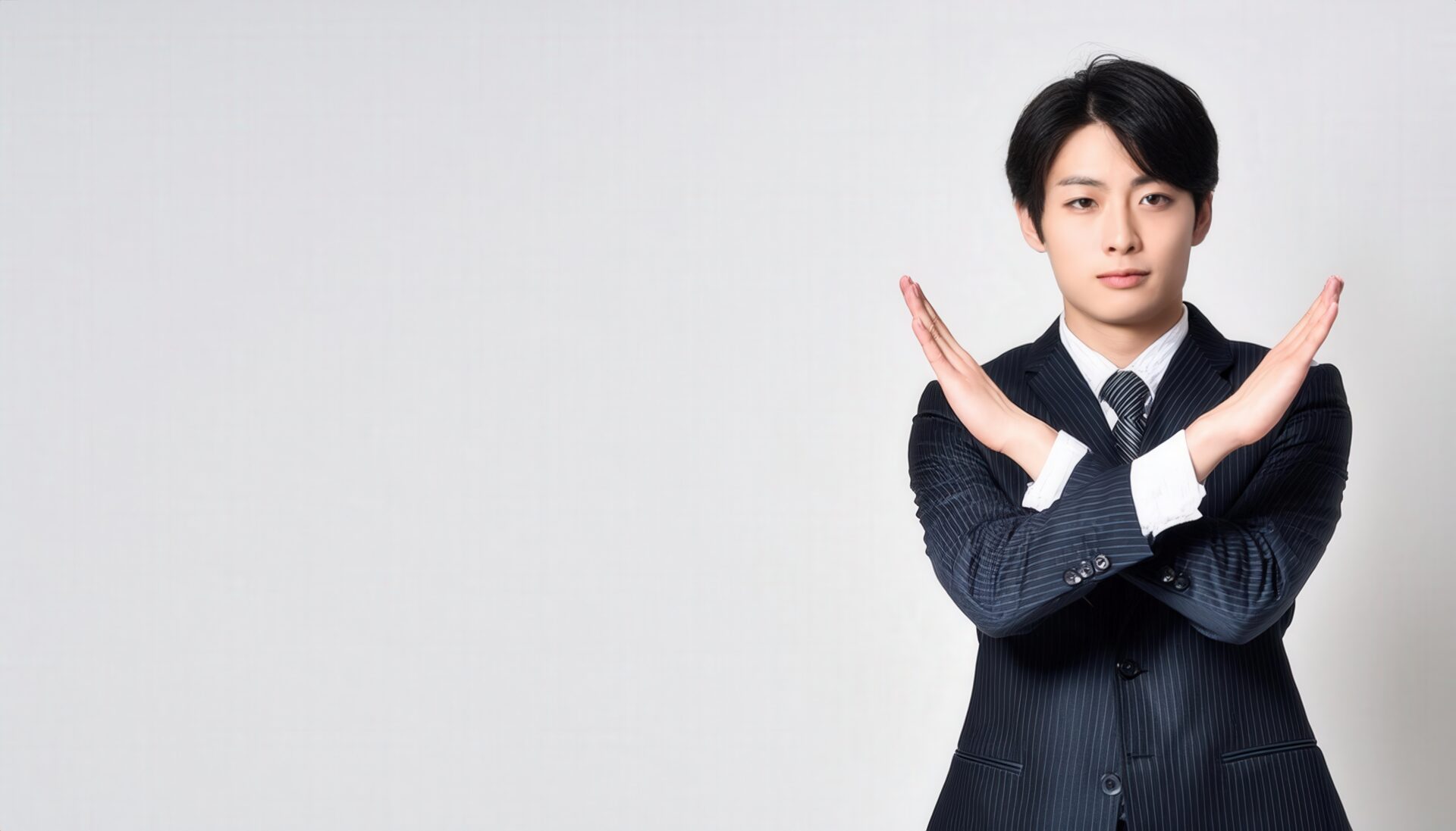 白背景でネイビーのスーツを着て腕をクロスしてNGサインを示す人