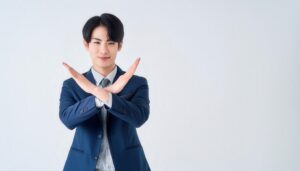白背景でネイビーのスーツを着て腕をクロスしてNGサインを示す人