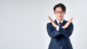 白背景でネイビーのスーツを着て腕をクロスしてNGサインを示す人