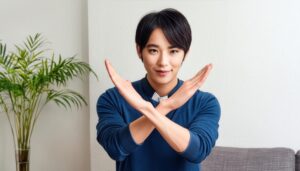 室内で青いトップスを着て腕をクロスしてNGサインを示す人