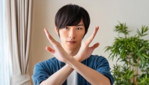 室内で青い羽織を着て腕をクロスしてNGサインを示す人