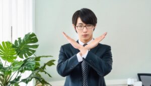 観葉植物のあるオフィスで腕をクロスしているスーツ姿の若い人