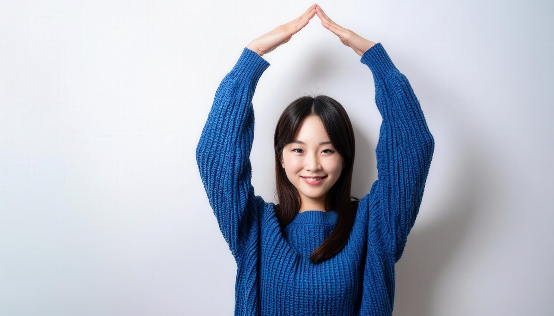 青いセーターで頭上に円を作っている若い人