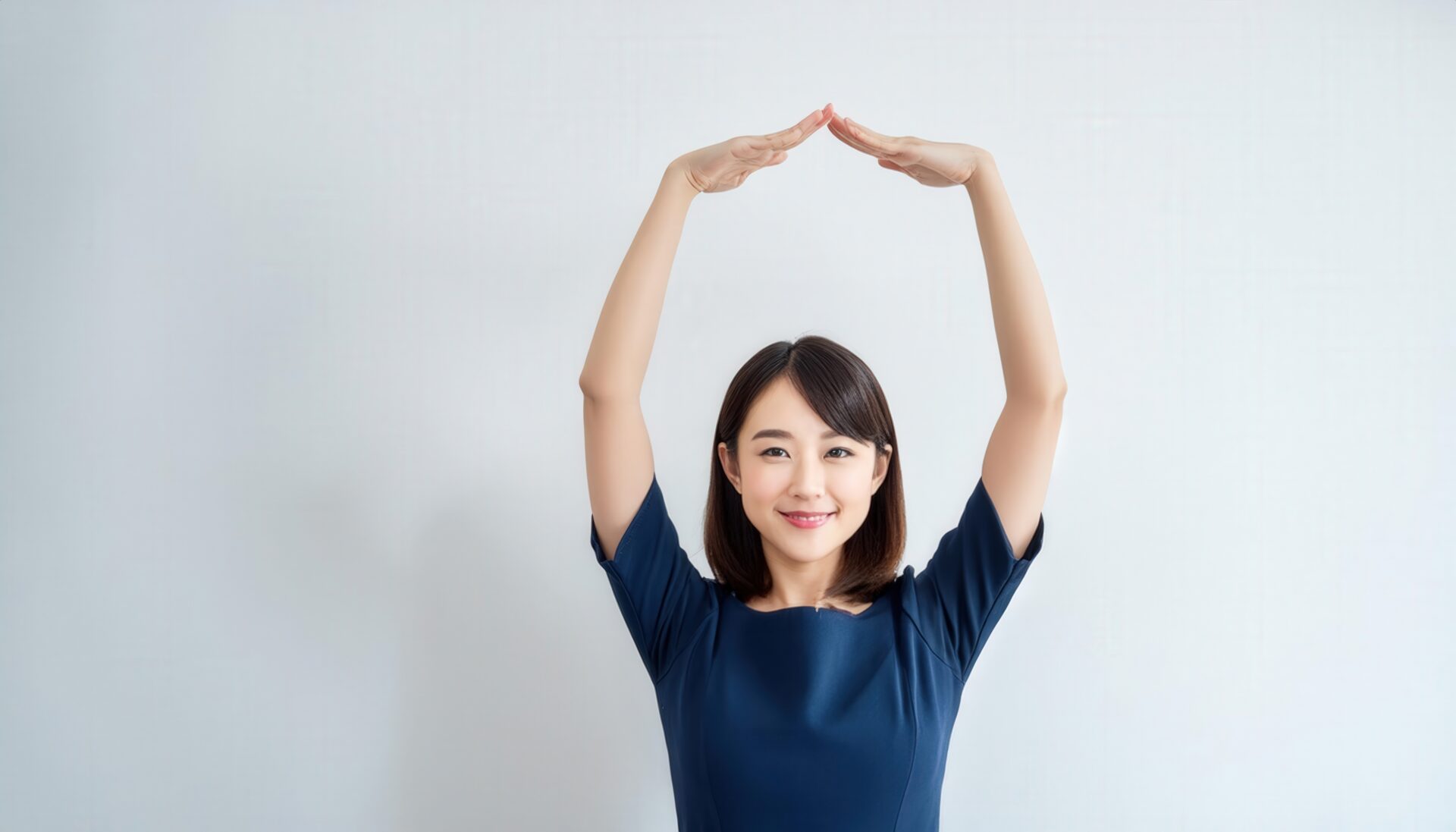 ネイビーのワンピースで頭上に円を作っている若い人