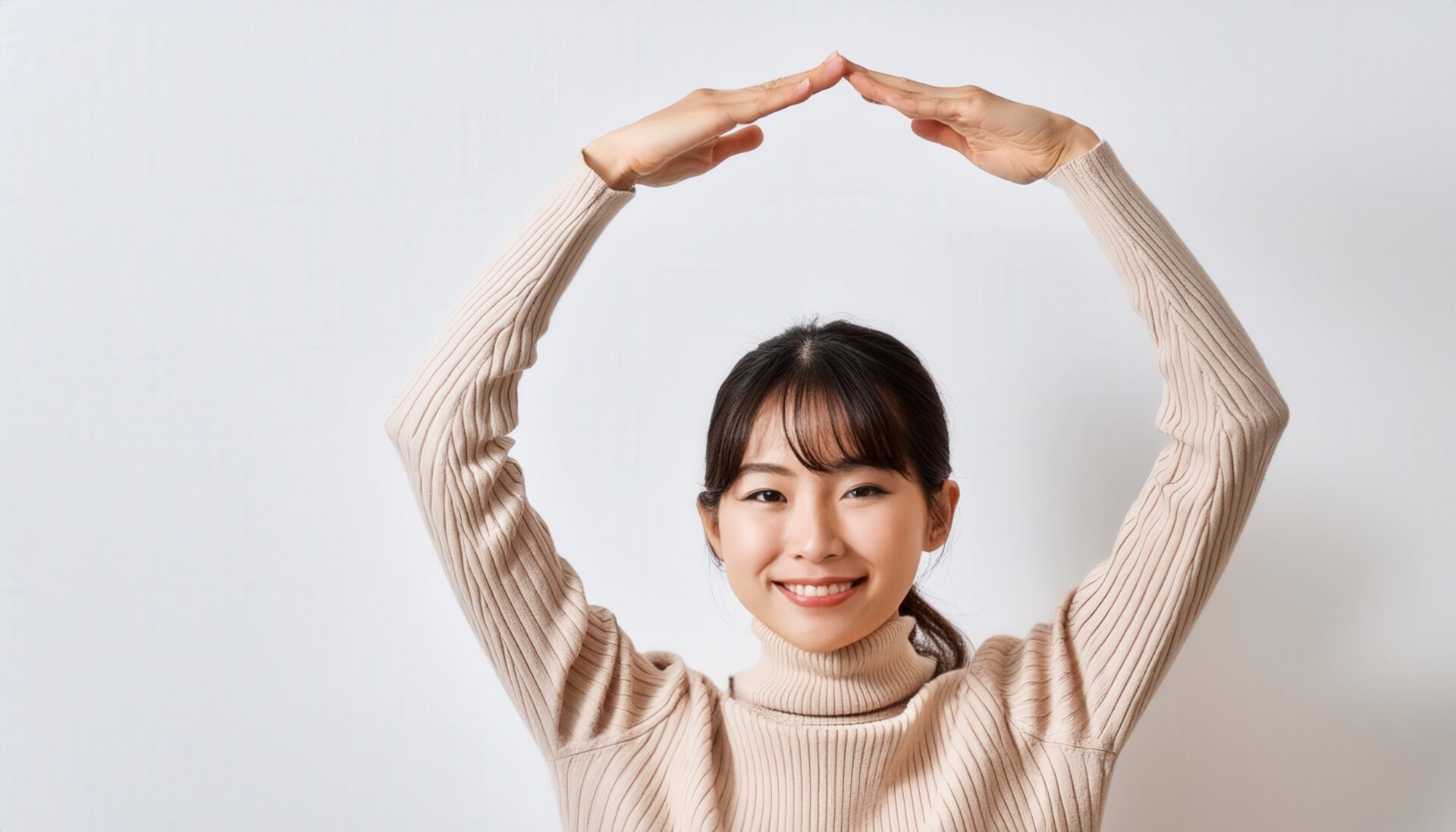 ベージュのセーターで頭上に円を作っている若い人