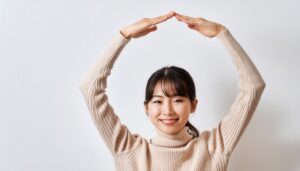 ベージュのセーターで頭上に円を作っている若い人