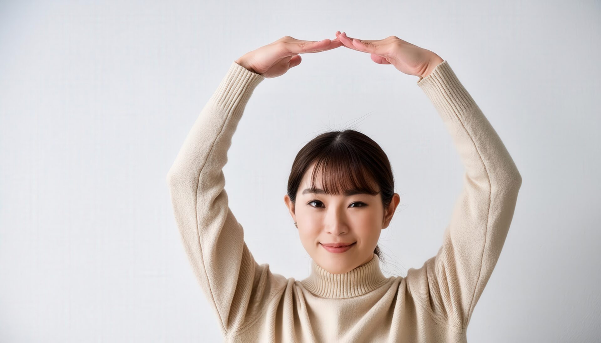 ベージュのセーターで頭上に円を作っている若い人