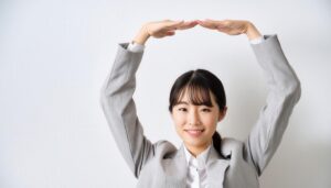 ライトグレーのスーツで頭上に円を作っている若い人