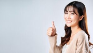 ベージュのカーディガンでグッドサインをしている若い人