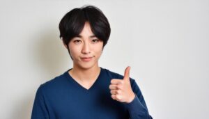 ダークカラーのセーター姿の若い男性が親指を立てる