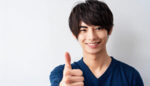シンプルな背景で親指を立てる笑顔の若い男性