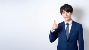 白背景でストライプのネクタイを締めた若者がサムズアップ