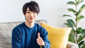 室内でサムズアップをする人物