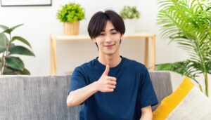 ソファに座って親指を立てる人物