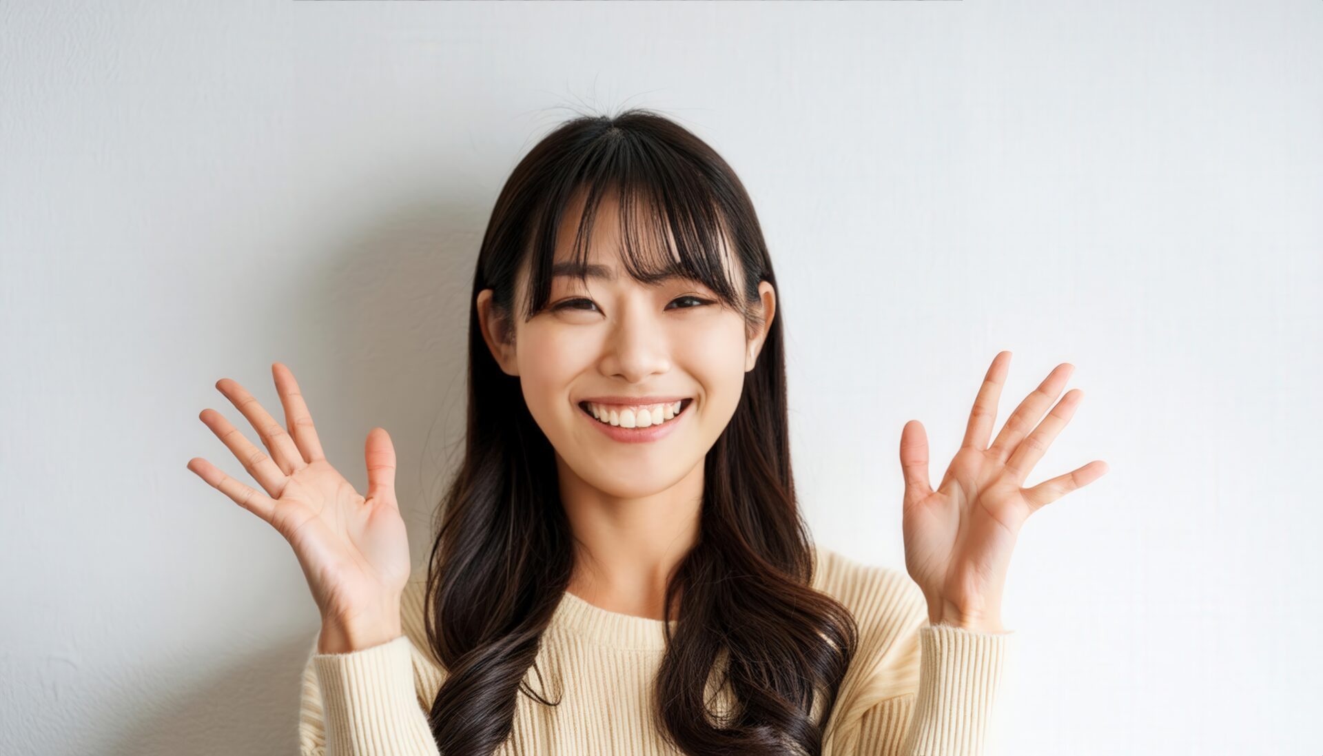 白背景で両手を広げるベージュのトップスを着た若い女性