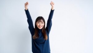 白背景で両腕を上げるセーター姿の若い女性