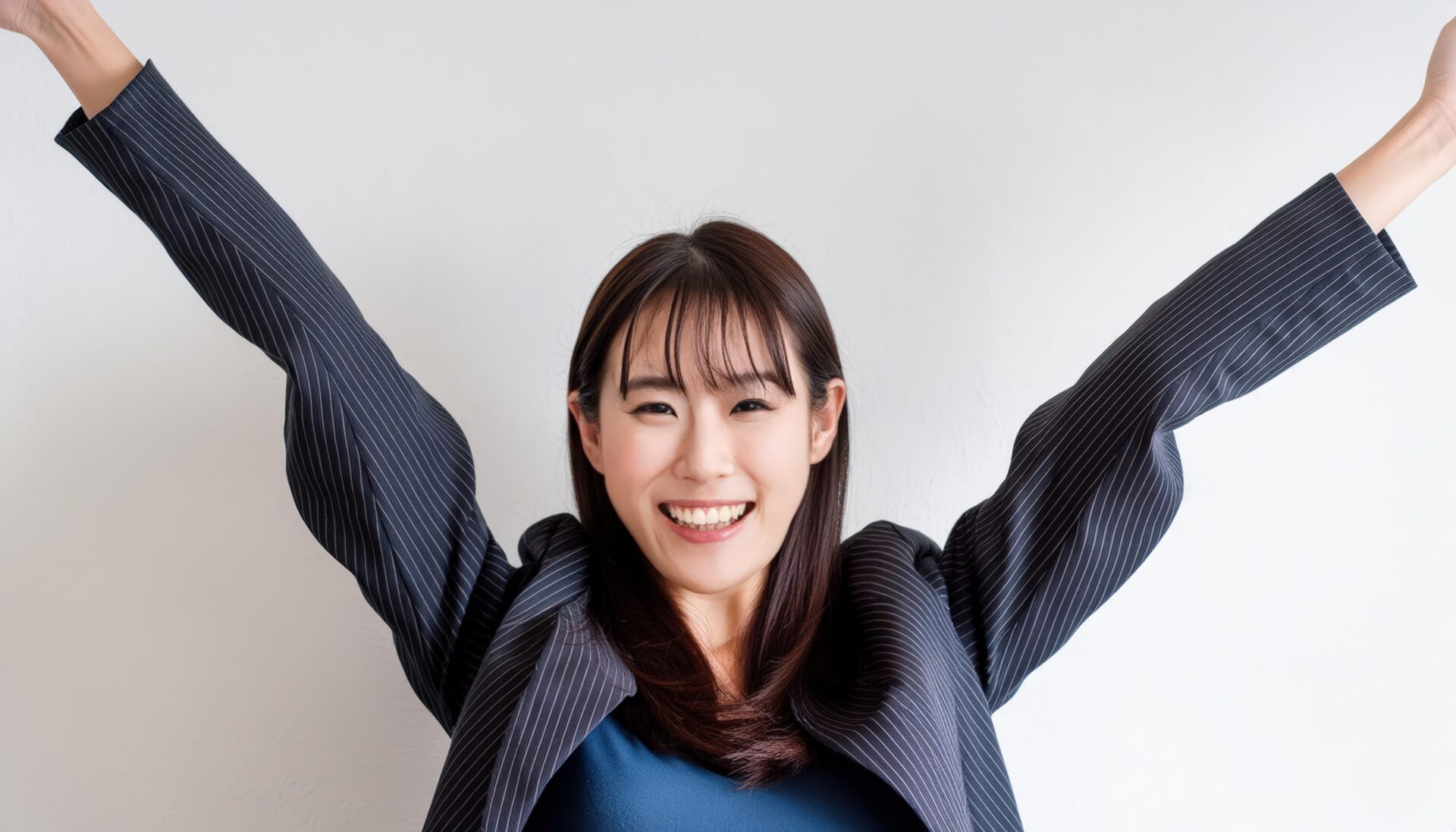 白背景で両腕を上げるジャケット姿の若い女性