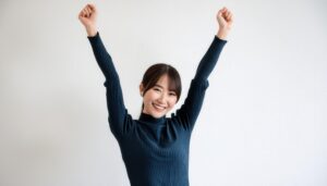 白背景で腕を上げる笑顔の若い女性