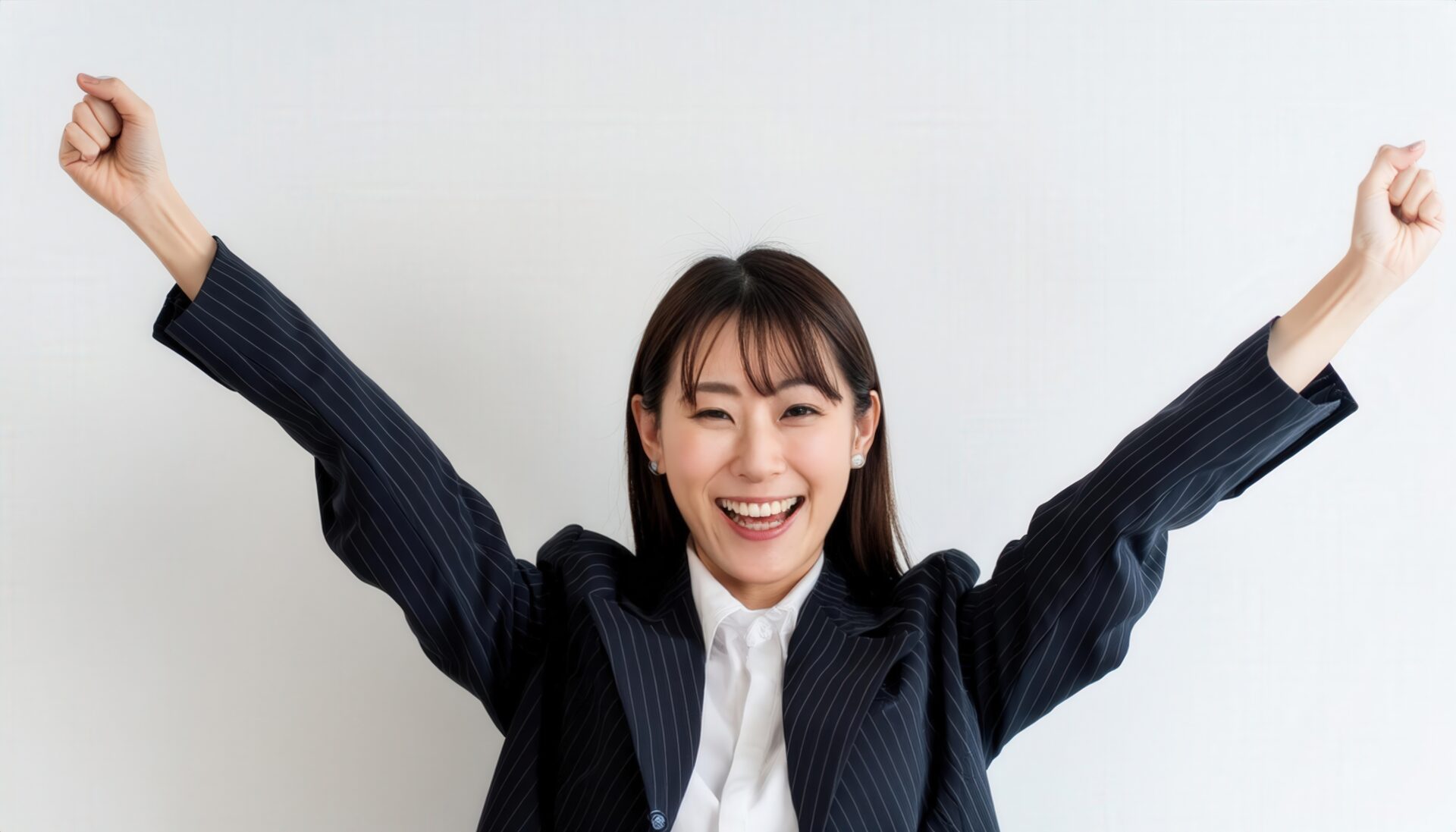 白背景で腕を上げて喜ぶスーツ姿の若い女性