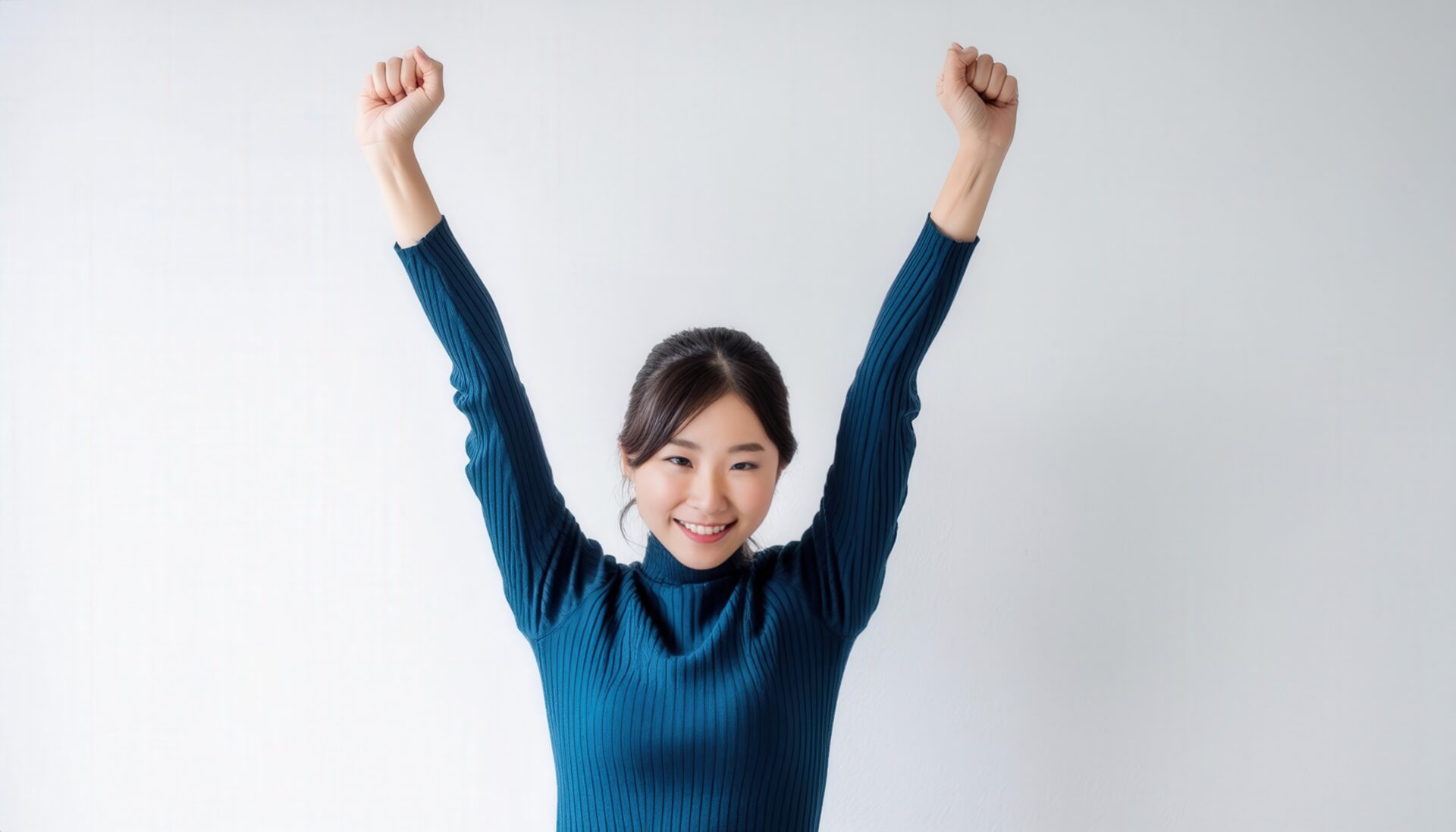 白背景で腕を高く上げる笑顔の若い女性（タートルネック）