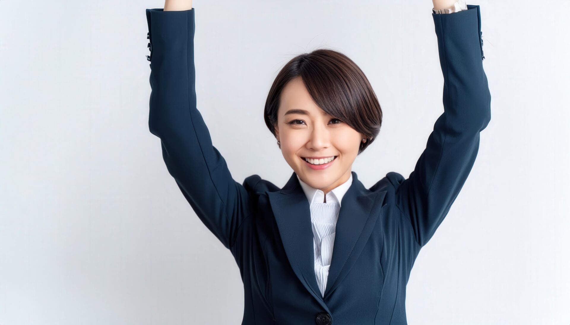 白背景で腕を上げる笑顔の若い女性（ショートヘア）