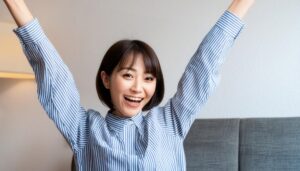 室内で万歳する笑顔の若い女性（ショートヘア・ストライプシャツ）