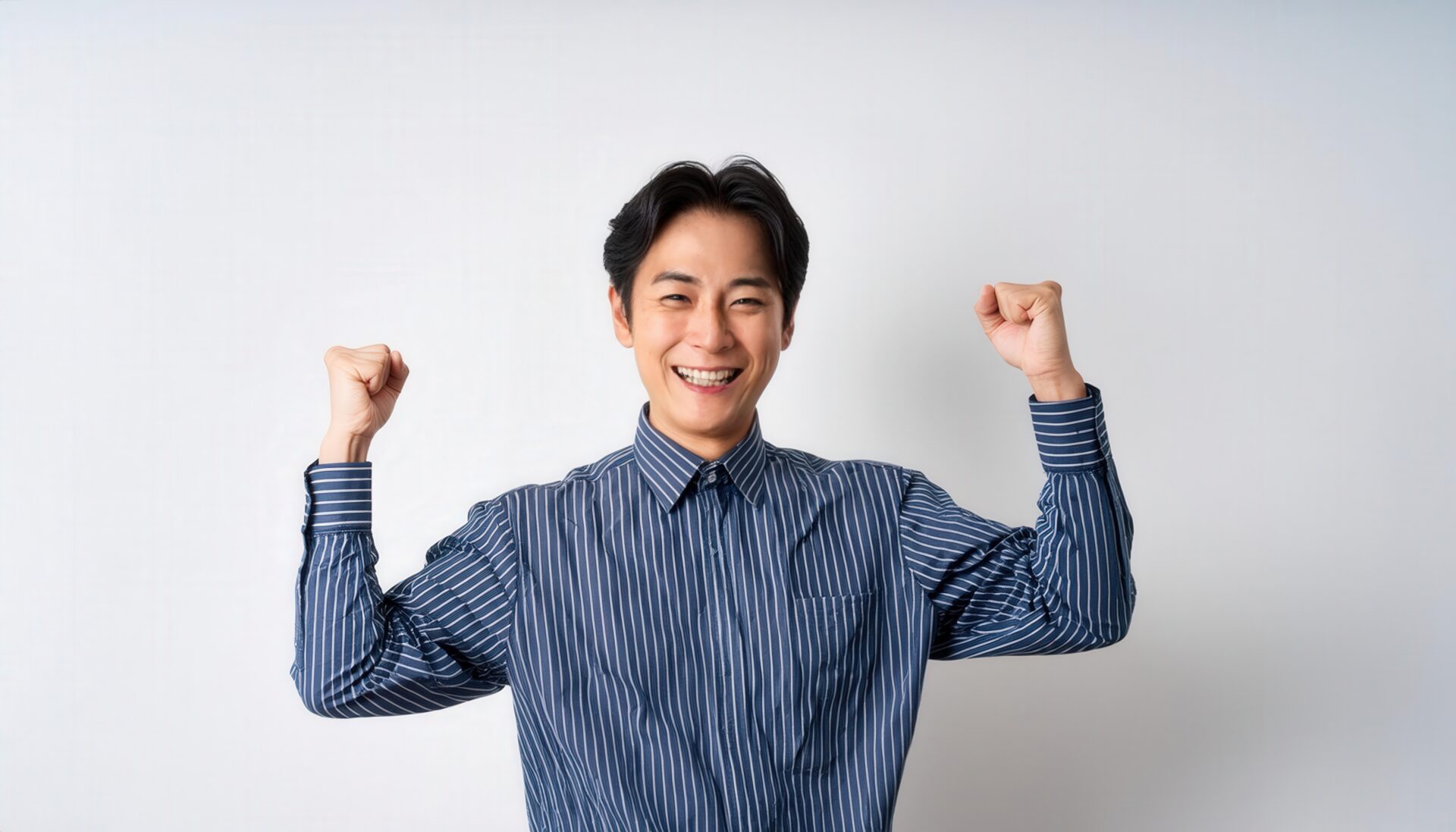 白背景でガッツポーズをする若い男性（ストライプシャツ）