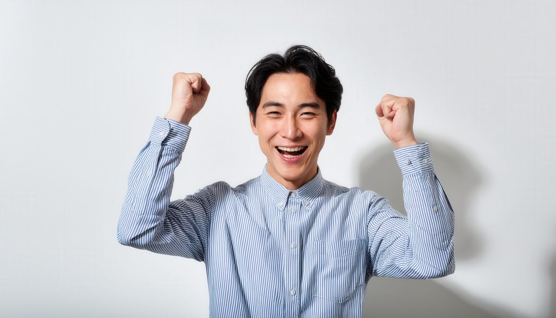白背景で拳を上げる若い男性（ストライプシャツ）
