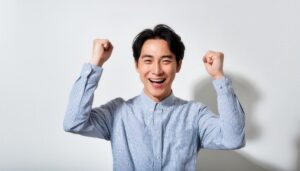 白背景で拳を上げる若い男性（ストライプシャツ）