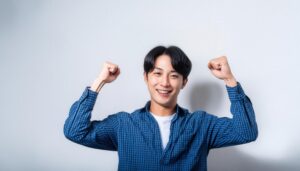 白背景でガッツポーズをする笑顔の若い男性（チェックシャツ）