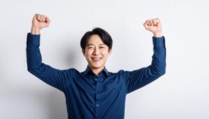白背景で拳を上げる笑顔の若い男性（ネイビーシャツ）