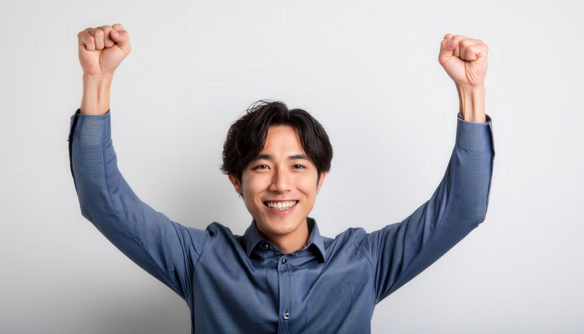 白背景でガッツポーズをする笑顔の若い男性（パターンシャツ）