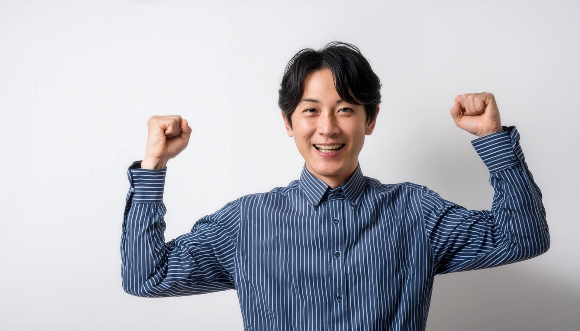 白背景でガッツポーズをする笑顔の若い男性（ストライプシャツ・前髪あり）