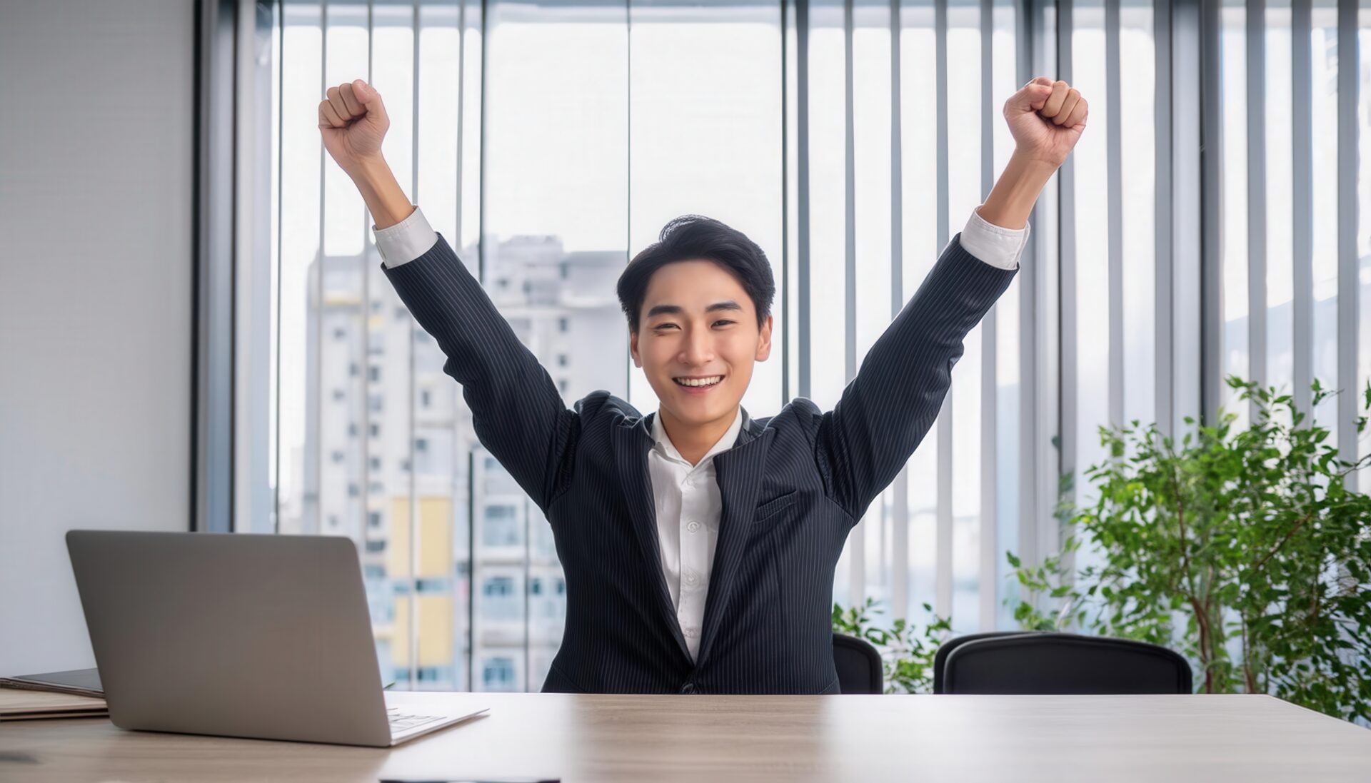 オフィスでガッツポーズをする若い男性（大きな窓のある室内）