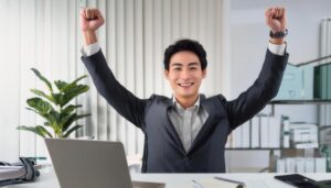 オフィスでガッツポーズをする若い男性（デスク・パソコンあり）