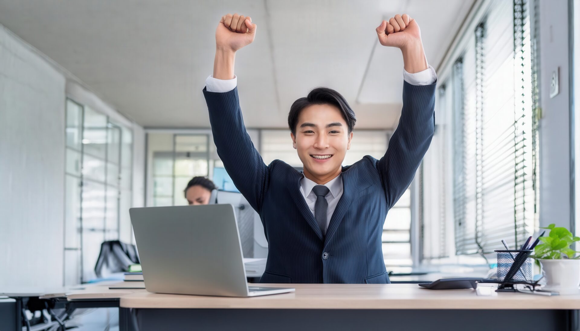 オフィスでガッツポーズをする若い男性（ノートPCと書類がある）