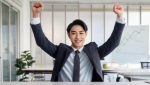 オフィスでガッツポーズをする若い男性（ビジネスグラフ背景）